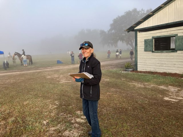 Volunteer jump judge with a clipboard on a foggy morning at the venue